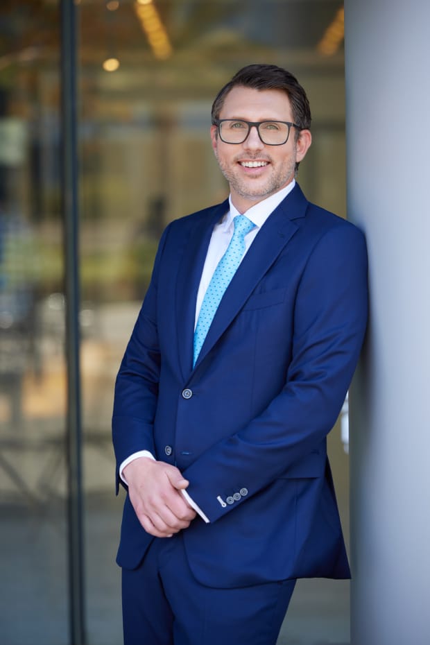Business headshot of a man in a navy suit and light blue tie photographed on location in Los Angeles