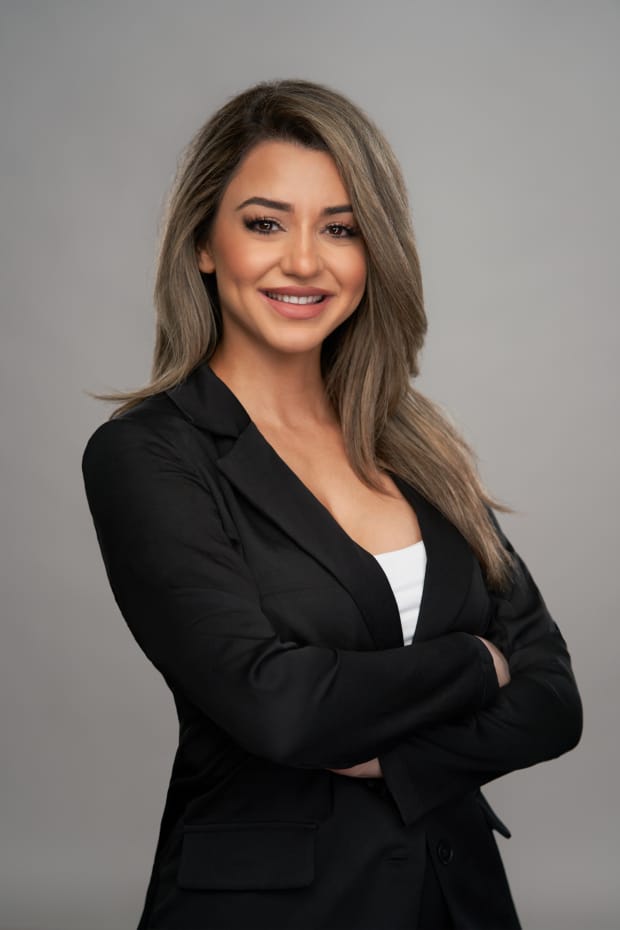 Professional business headshot of a woman in a black blazer on a grey studio background