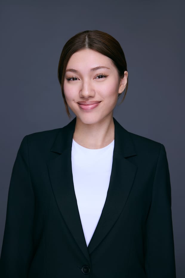 LinkedIn headshot of a woman in a navy blazer on a grey studio background