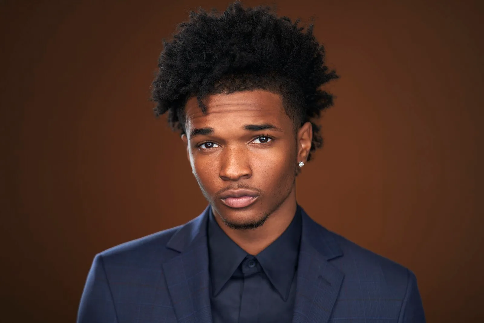 Isaiah Hill in a navy plaid suit on a warm brown backdrop - celebrity headshot by Headshots LA in Los Angeles.